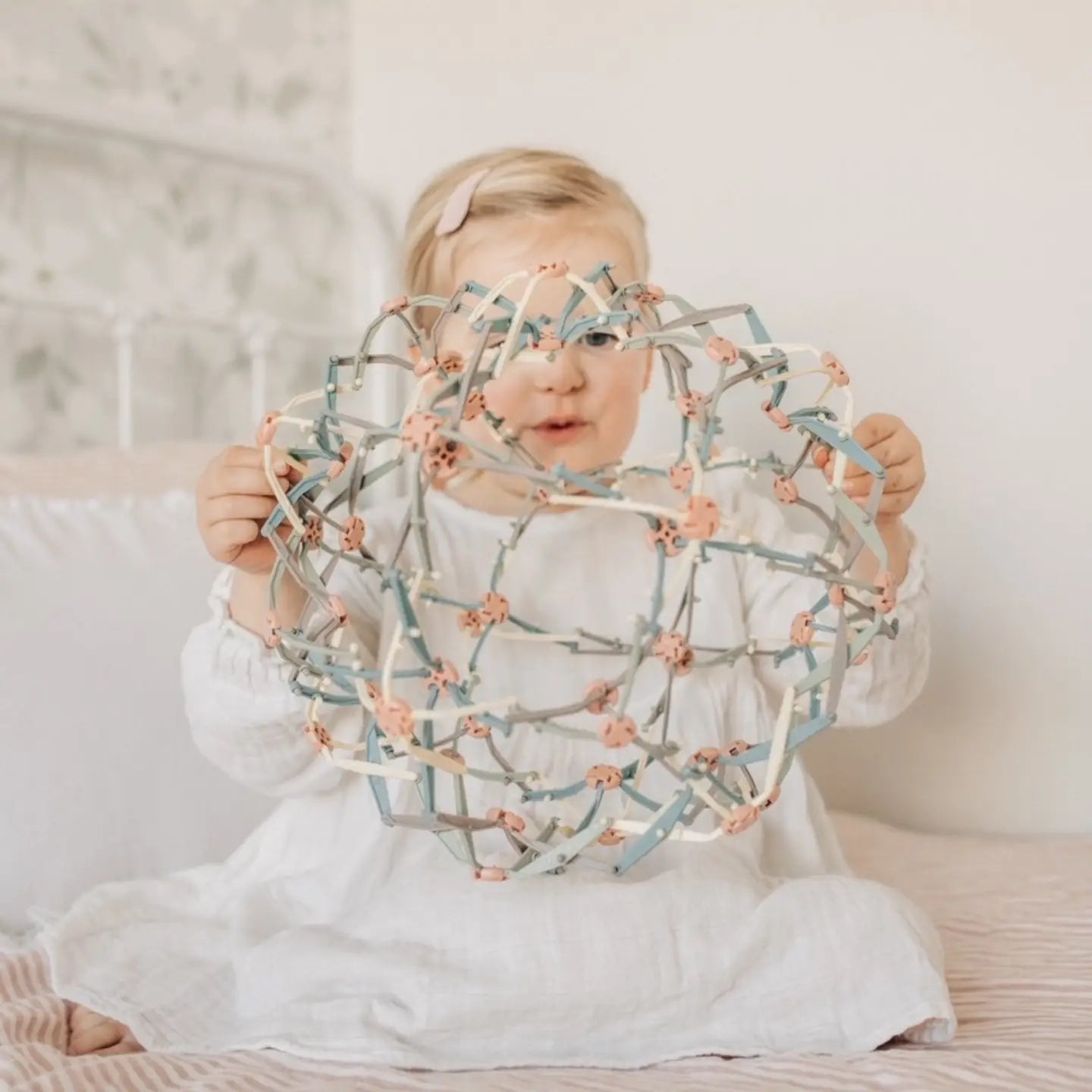 Mindfulness Magic Ball breathing toy for kids shown in its expanded state with calming colors on a light background being held by a little girl. 